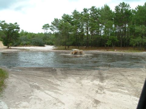 1995 Ford Bronco - A vehicle navigates through a muddy, watery area with tire tracks marking the sandy terrain.