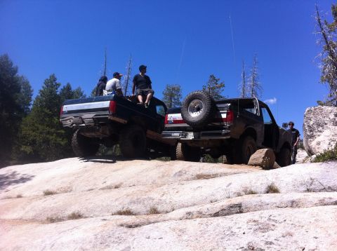 1990 Ford Bronco - Off-roading adventure with friends on a sunny day, navigating challenging terrain.