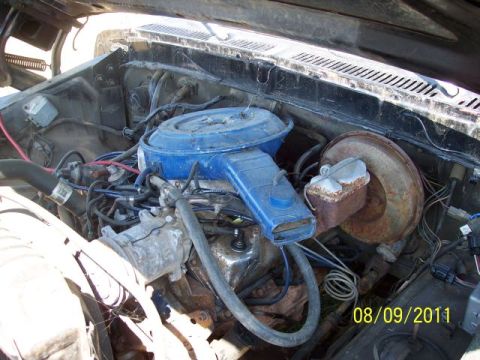 1978 Ford Bronco - The engine compartment shows various hoses, wiring, and a blue air filter housing.