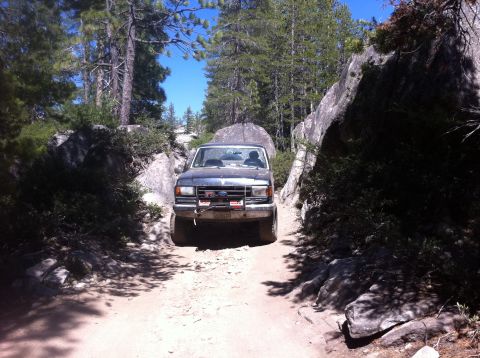 1990 Ford Bronco - This 1990 Ford Bronco navigates a narrow dirt path surrounded by large rocks and trees.