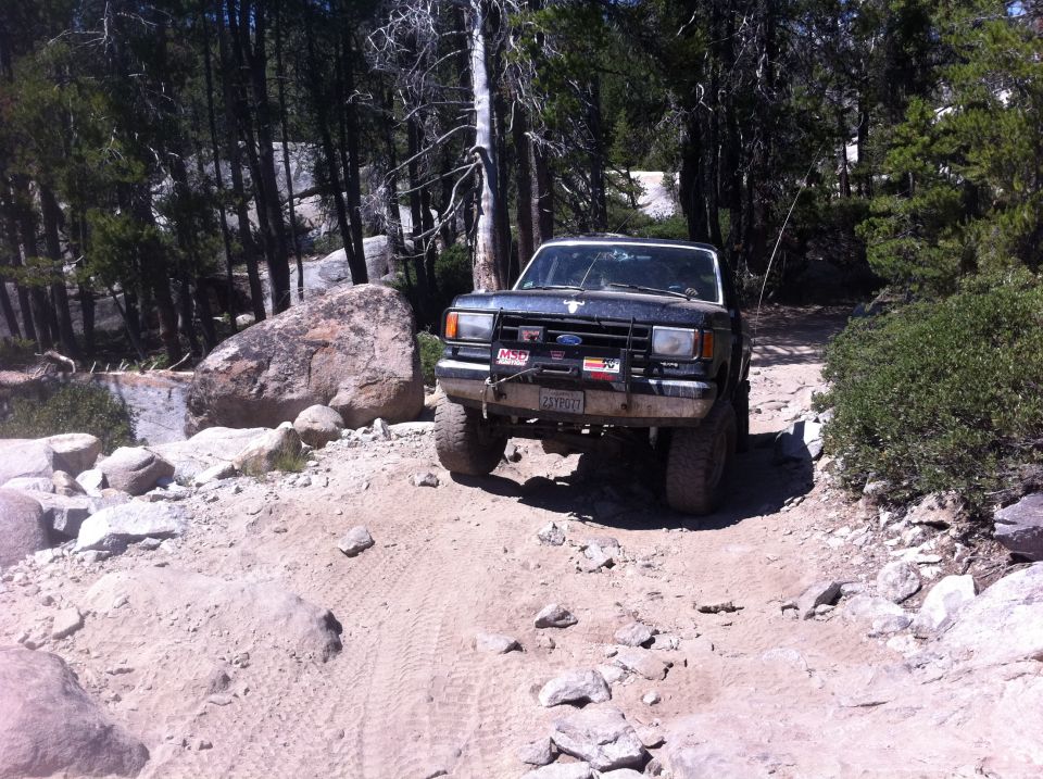 Ford Bronco on a dirt trail with trees and rocks