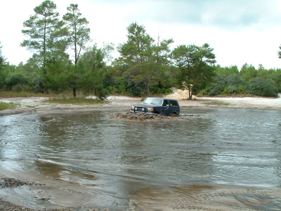 Dark 1995 Ford Bronco driving through muddy water
