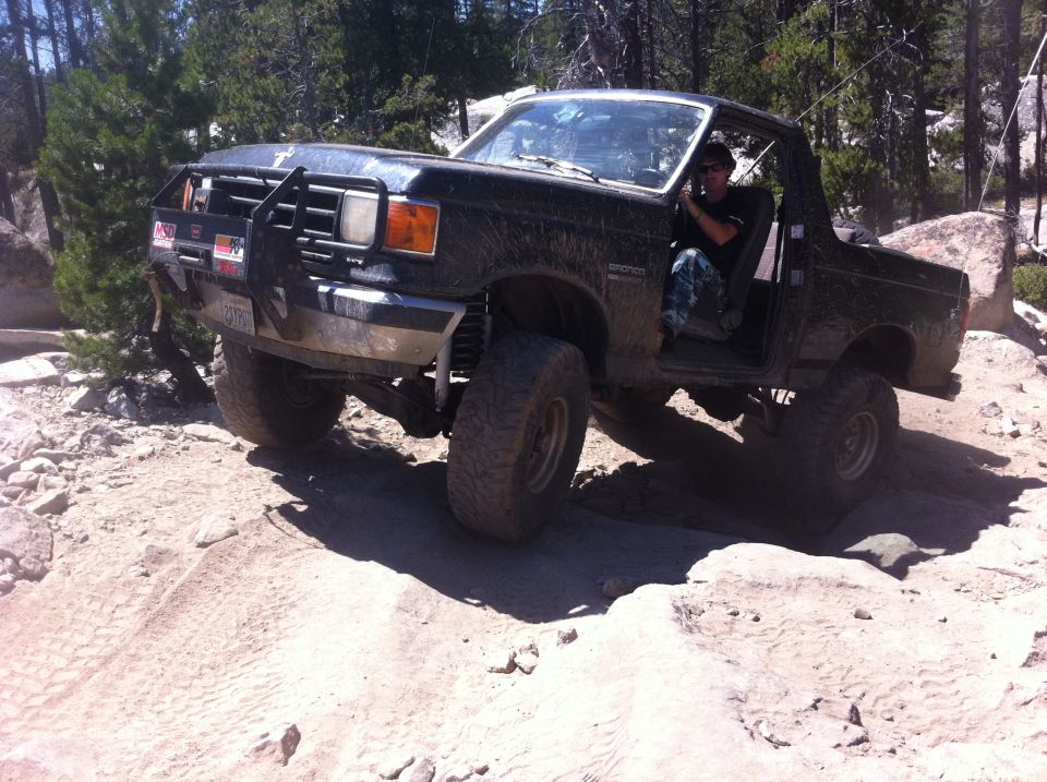 Black Ford Bronco off-roading on rocky terrain, driver visible inside