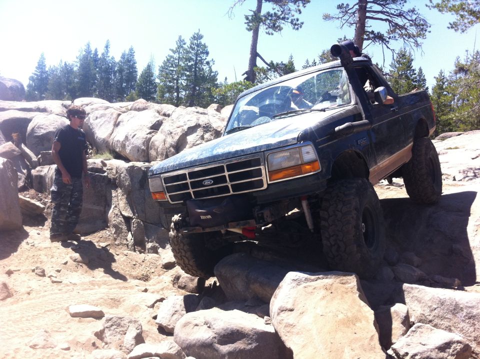 Dark blue SUV with snorkel on rocks. Appears to be a 1992 Ford Bronco