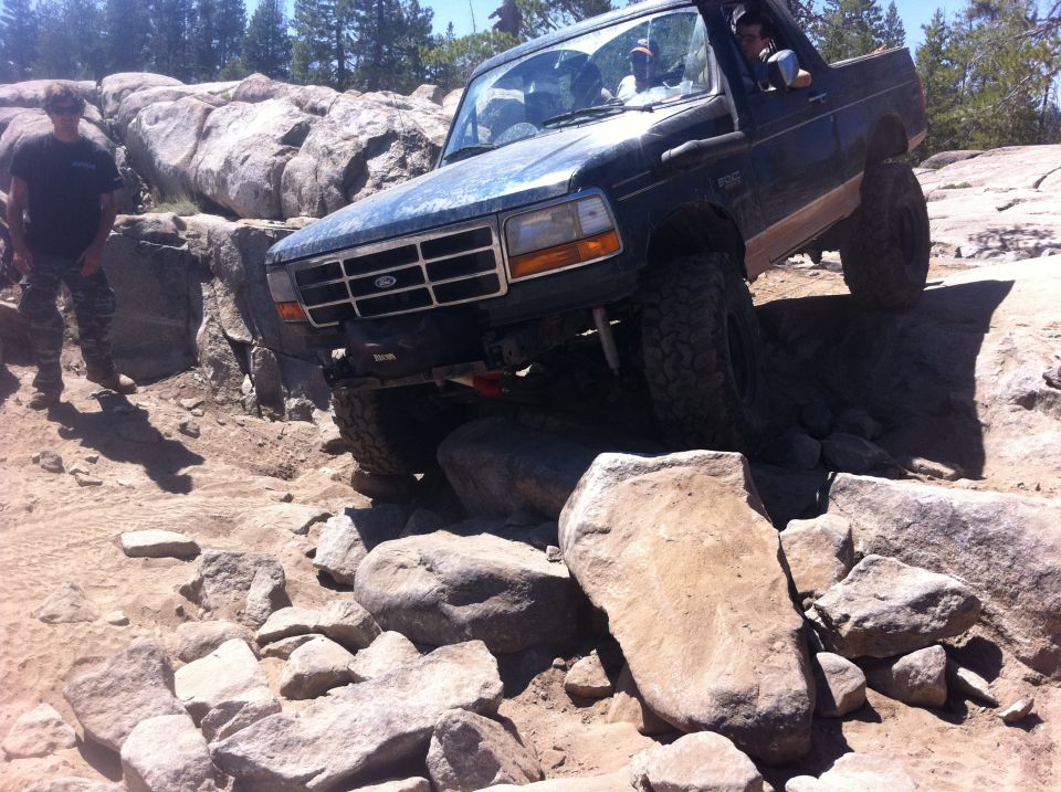 1990 Ford Bronco navigating a rocky trail, front wheels high