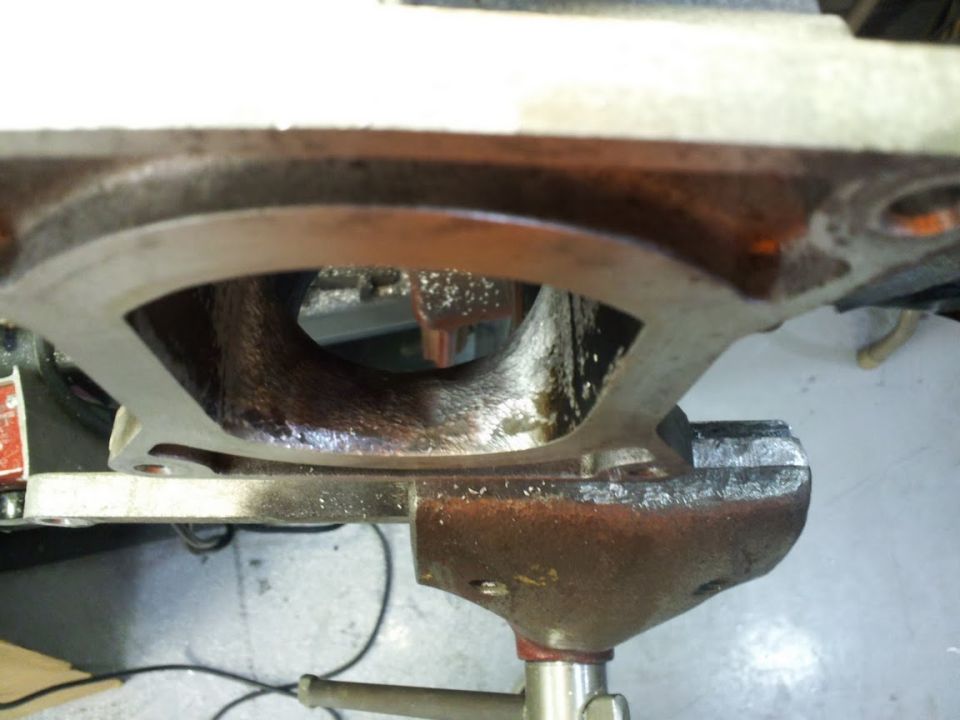 Engine intake manifold held in a vise, showing internal ports