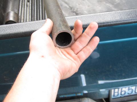 1984 Ford Bronco - Hand holding a metal pipe. The background appears to be the bed of a teal pickup truck.