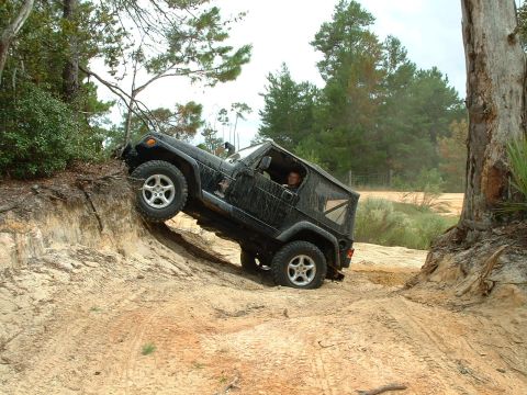 1995 Ford Bronco - A black Jeep Wrangler navigates a challenging sandy terrain during an off-road excursion.