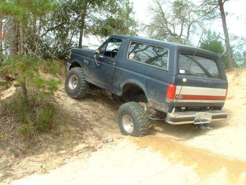1995 Ford Bronco - This 1995 Ford Bronco navigates a challenging sandy incline, its off-road capabilities with prominent tires.