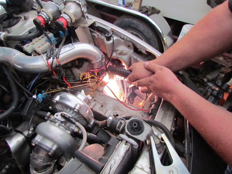Engine bay with twin turbos and custom piping. Someone is working on wiring