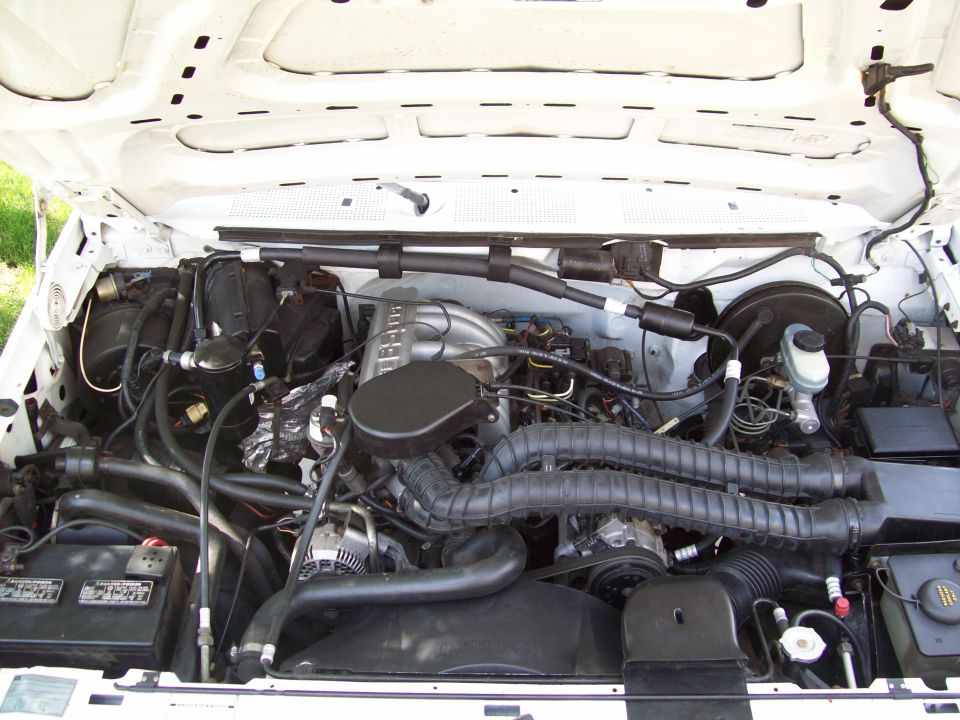 Engine bay of a white pickup showing EFI V8, air box and intake tube