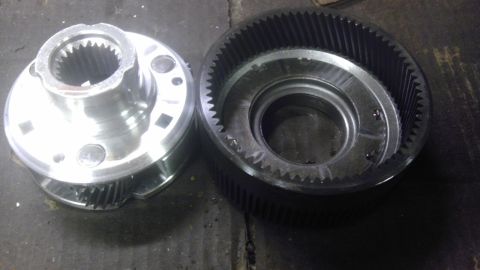 1989 Ford Bronco - Two metal transmission components with visible gears are laid out on a dark surface.