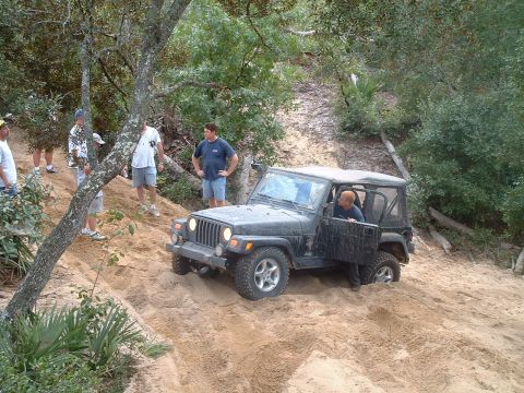1995 Ford Bronco - A group of people watch as a Jeep Wrangler tackles a challenging sandy incline during an off-road excursion.