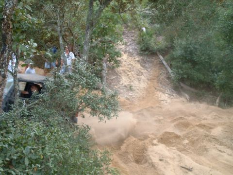 1995 Ford Bronco - A 1995 Ford Bronco navigates a challenging sandy incline, creating a dust cloud as it ascends.