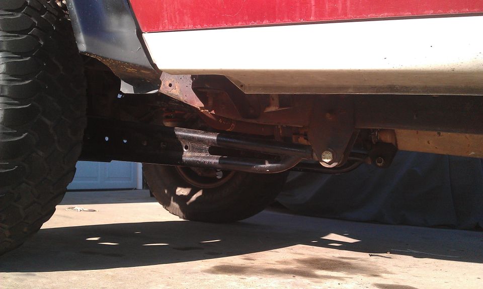 Red and white truck frame with large tire and suspension components visible