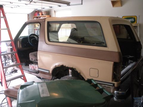 1987 Ford Bronco - This two-tone tan and brown 1987 Ford Bronco is parked inside a garage, appearing to be in a state of repair or restoration.