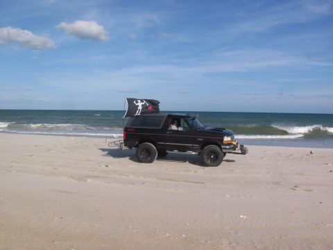 1995 Ford Bronco - Ford Bronco on the beach with a pirate-style flag flying.