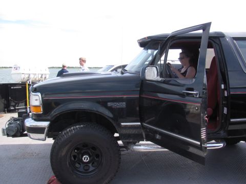 1995 Ford Bronco - A black 1995 Ford Bronco is parked on a ferry deck with its doors open, while a woman sits in the driver's seat.