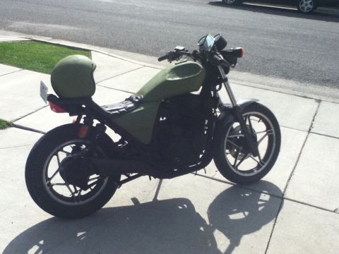 2002 Kawasaki Ninja - A green motorcycle with a green helmet resting on its seat is parked on a sidewalk.