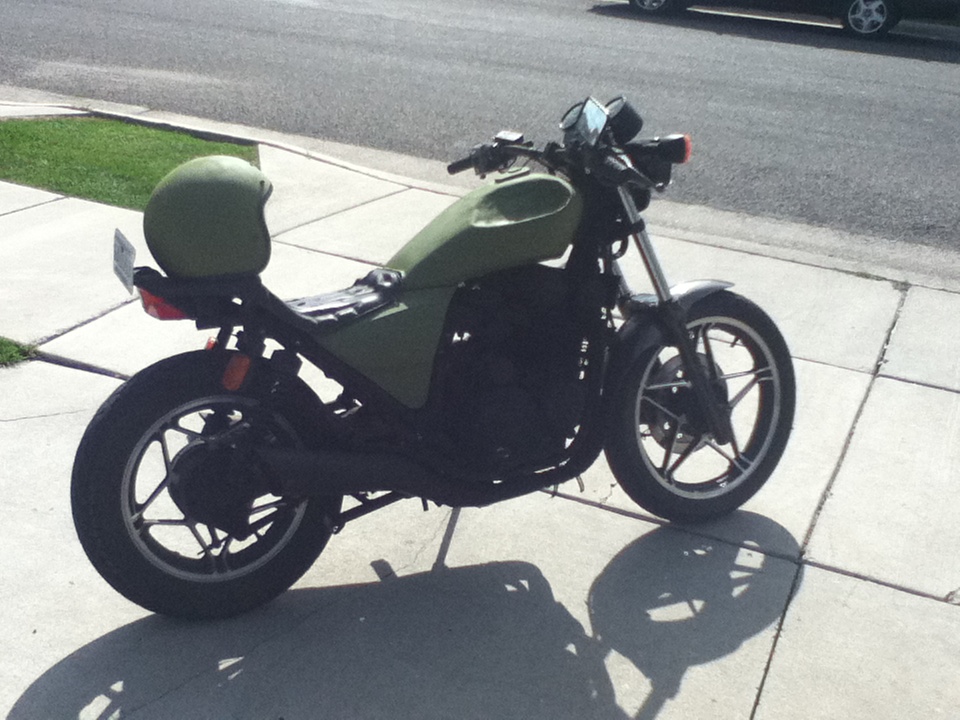 Side view of a green motorcycle with a green helmet on the seat