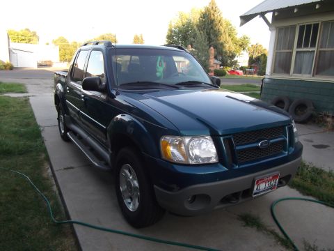 1988 Chevrolet Suburban - A dark teal Ford Explorer Sport Trac is parked in front of a house.