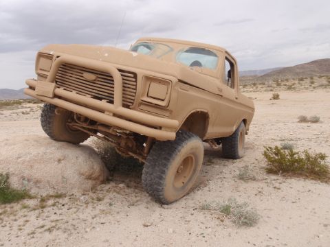 1978 Ford Bronco - This tan Ford F-Series truck is navigating rocky terrain in a desert landscape.