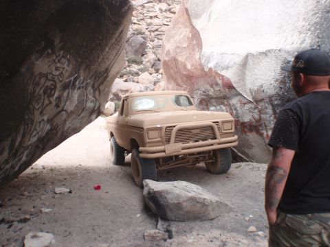 1978 Ford Bronco - Pickup truck driving through a narrow canyon with large rock formations.