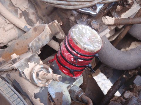 1978 Ford Bronco - Makeshift repair on an engine part using tape, plastic, and zip ties.