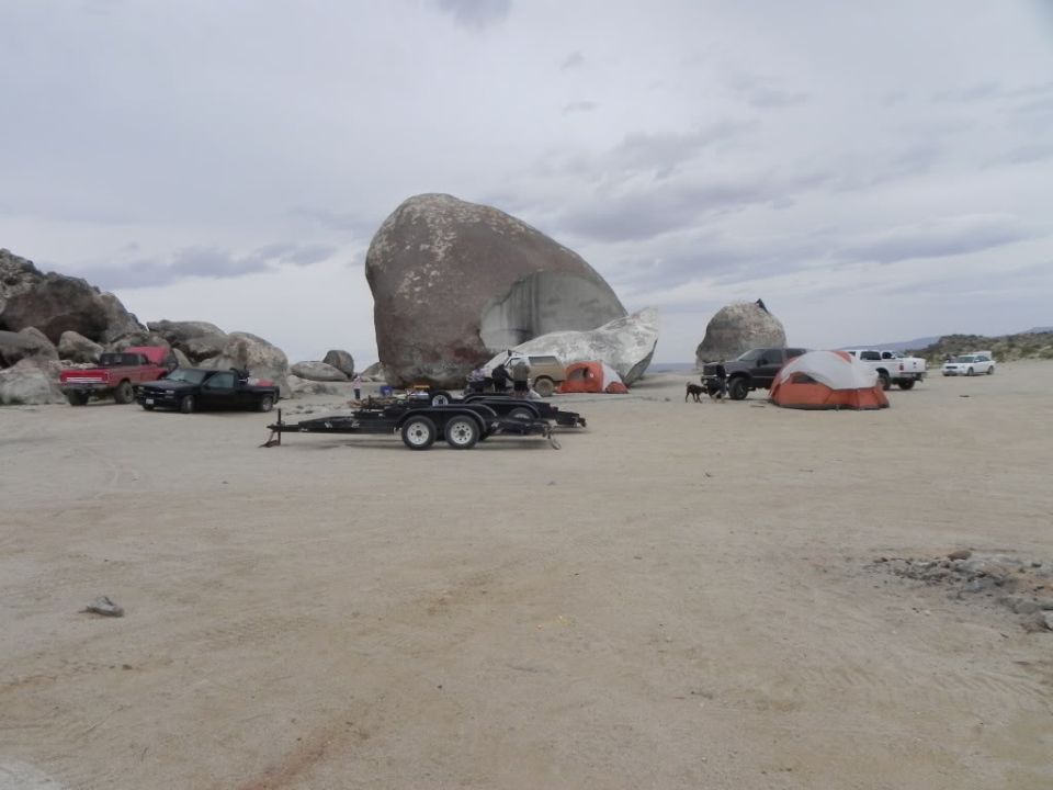 Empty tandem-axle trailer and pickups camped at Giant Rock in the desert