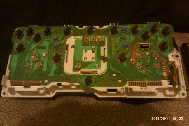 Back of a car's dashboard circuit board with many black and blue connectors