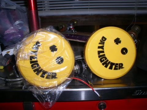 1979 Ford Bronco - These two yellow lights feature a smiley face design and the brand name 'DAYLIGHTER' printed on them.