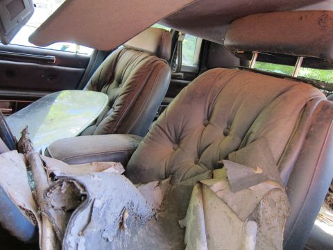 1991 Ford LTD Crown Victoria - The interior of a car shows significant wear and tear, with damaged seats and upholstery.
