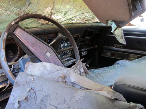 1991 Ford LTD Crown Victoria - The interior of a car shows significant damage, including a shattered windshield and debris on the dashboard.
