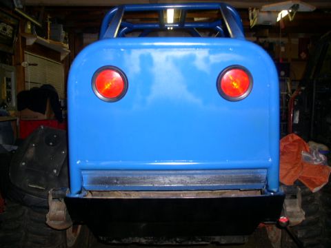1979 Ford Bronco - Rear view of a modified blue off-road vehicle with a prominent roll cage and round taillights.