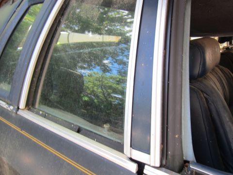 1991 Ford LTD Crown Victoria - Interior view of a car's door and window, with reflections visible on the glass.