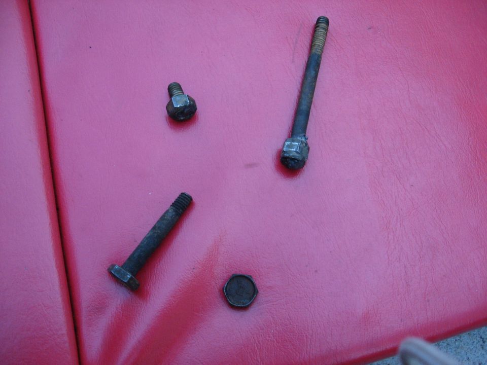 Three bolts and a round cap on a red surface