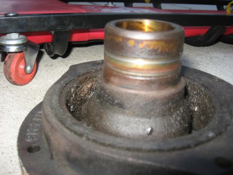1994 Ford Bronco - A close-up of a used crankshaft pulley, showing wear and debris, with a mechanic's creeper in the background.