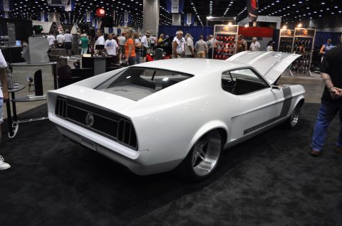 2007 Ford Mustang - A white 1969 Ford Mustang with racing stripes is displayed with its hood open at a car show.