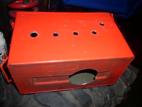 1979 Ford Bronco - An orange metal box with various holes and openings is shown, resting on a large tire.