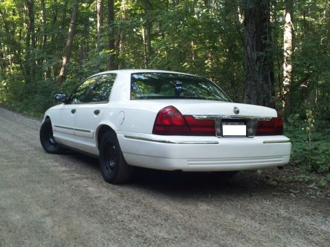 2000 Mercury Grand Marquis - A white 2000 Mercury Grand Marquis is parked on a dirt road surrounded by trees.