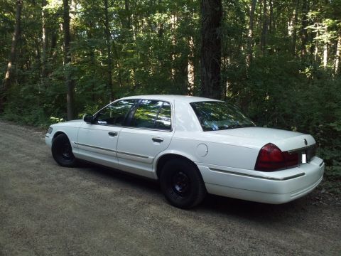 2000 Mercury Grand Marquis - White 2000 Mercury Grand Marquis parked on a dirt road surrounded by trees.