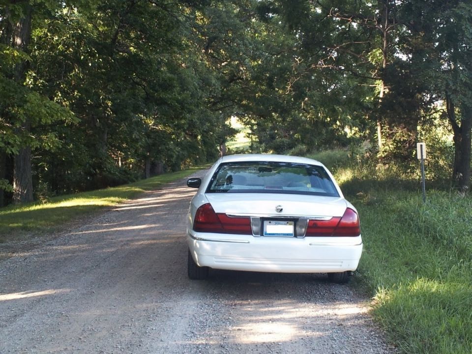 White 2000 Mercury Grand Marquis parked on a gravel road, rear view