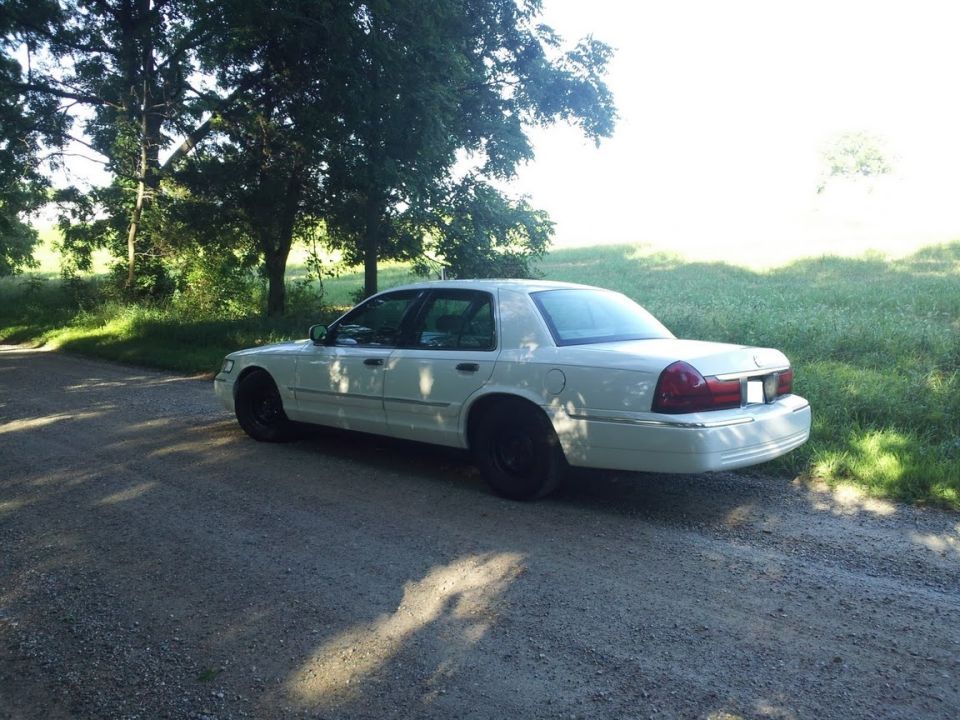 2000 Mercury Grand Marquis parked on a gravel road with trees and grass in the background