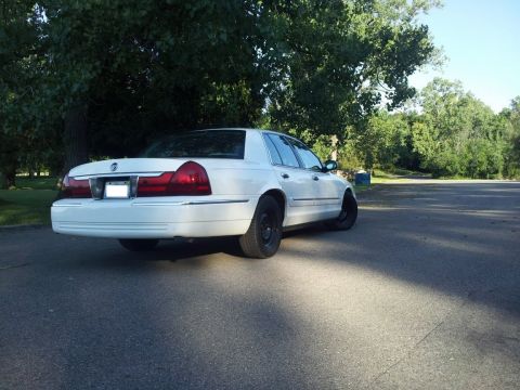 2000 Mercury Grand Marquis - A white 2000 Mercury Grand Marquis is parked outdoors with trees in the background.