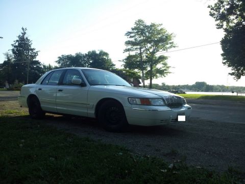 2000 Mercury Grand Marquis - A white 2000 Mercury Grand Marquis is parked outdoors near a body of water.