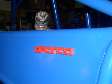 1979 Ford Bronco - Close-up of a red Bronco badge on a blue vehicle's side panel.