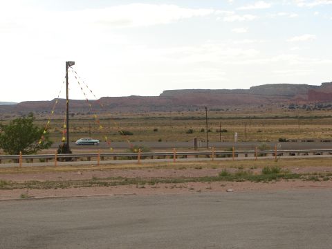 1992 Ford Taurus - A white sedan travels along a highway through a desert landscape under a cloudy sky.
