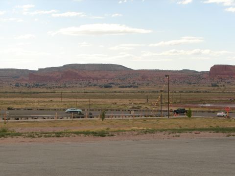 1992 Ford Taurus - Several vehicles travel along a highway with a vast, arid landscape and distant mountains under a partly cloudy sky.