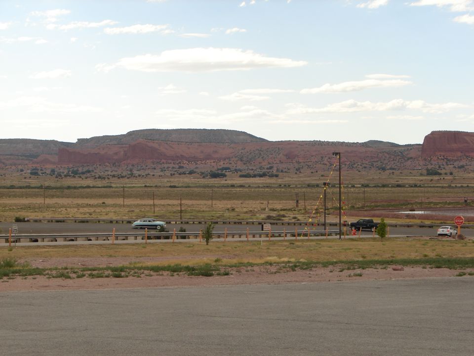 Cars driving on a highway with red rock formations in the background