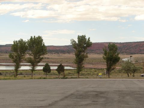1992 Ford Taurus - A lone white car is visible parked in a vast landscape with trees and distant mountains under a cloudy sky.